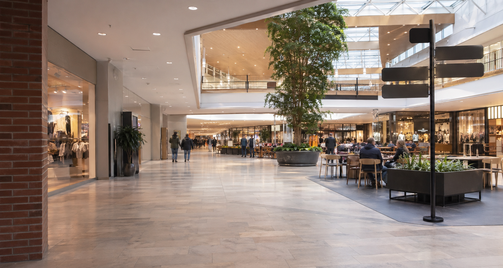 Ljust köpcentrum med butiker, sittplatser och besökare